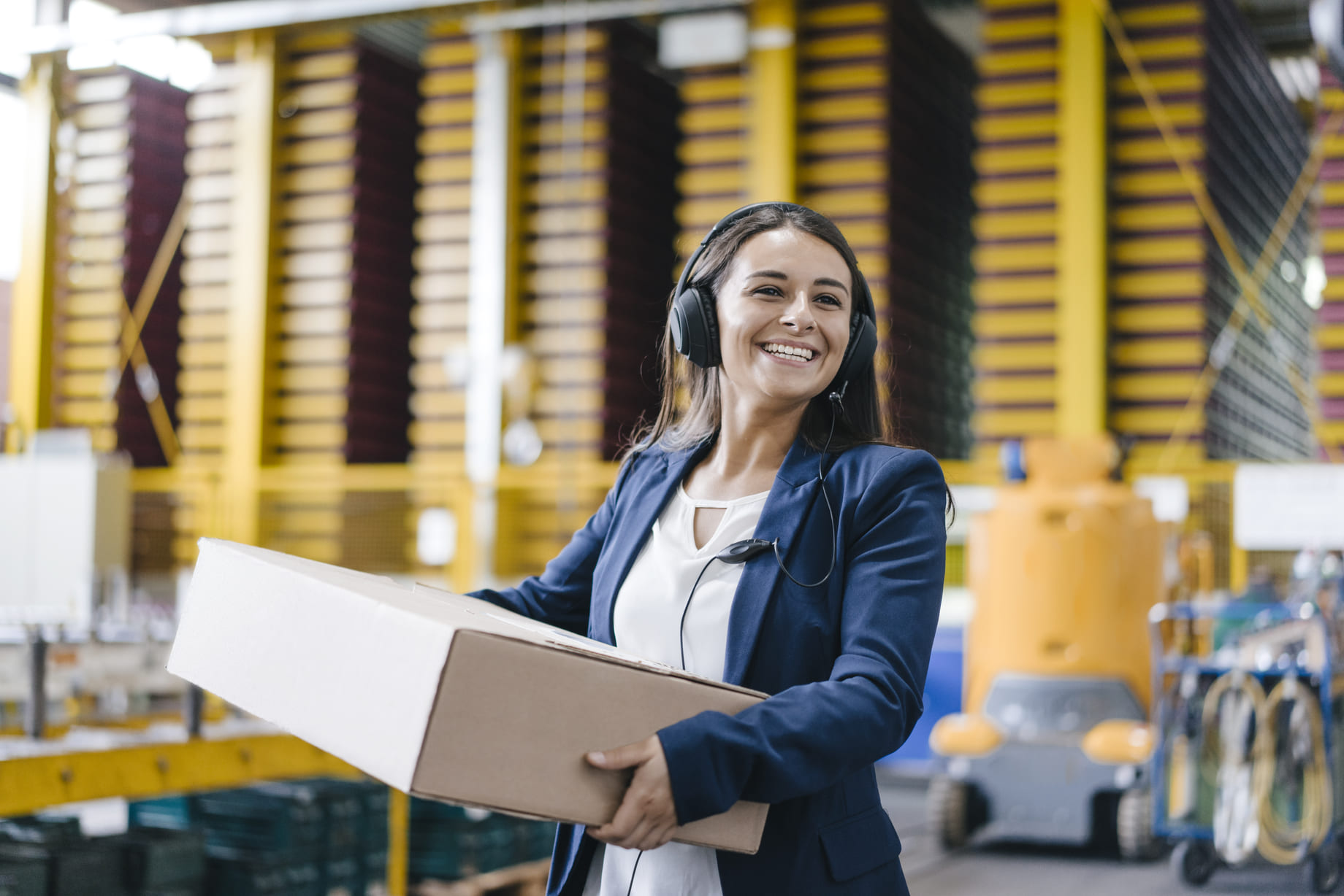 Trabajadora de envíos con paquete y auriculares.